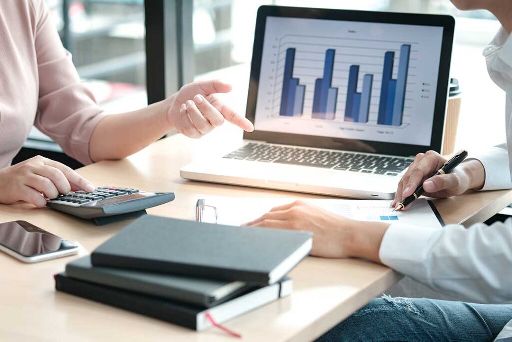 A person reviewing their checking account statement and debit card at a kitchen table.